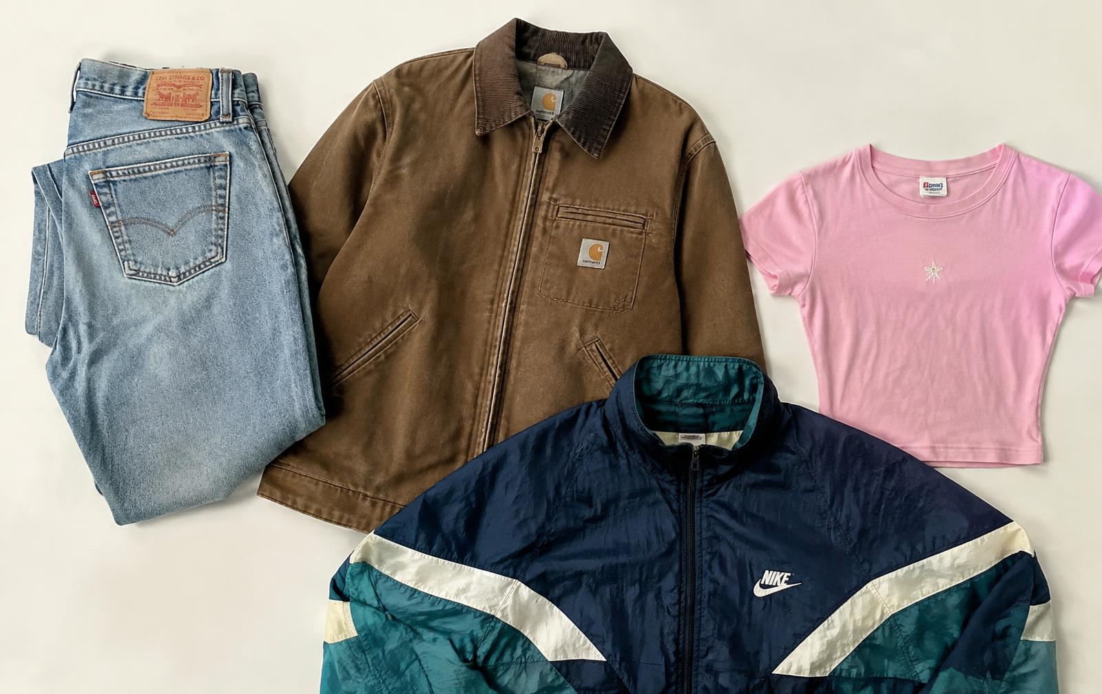 Flat-lay of vintage Levi's jeans, Carhartt jacket, Nike windbreaker and baby tee